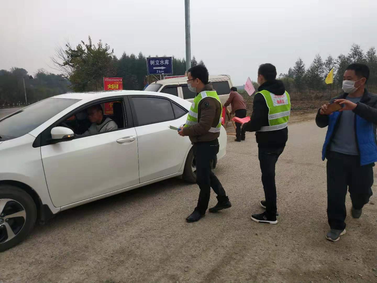 工作隊員協同村干部在路口發(fā)放宣傳材料照片.jpg
